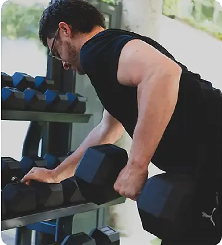 A person selecting a dumbbell from a rack
