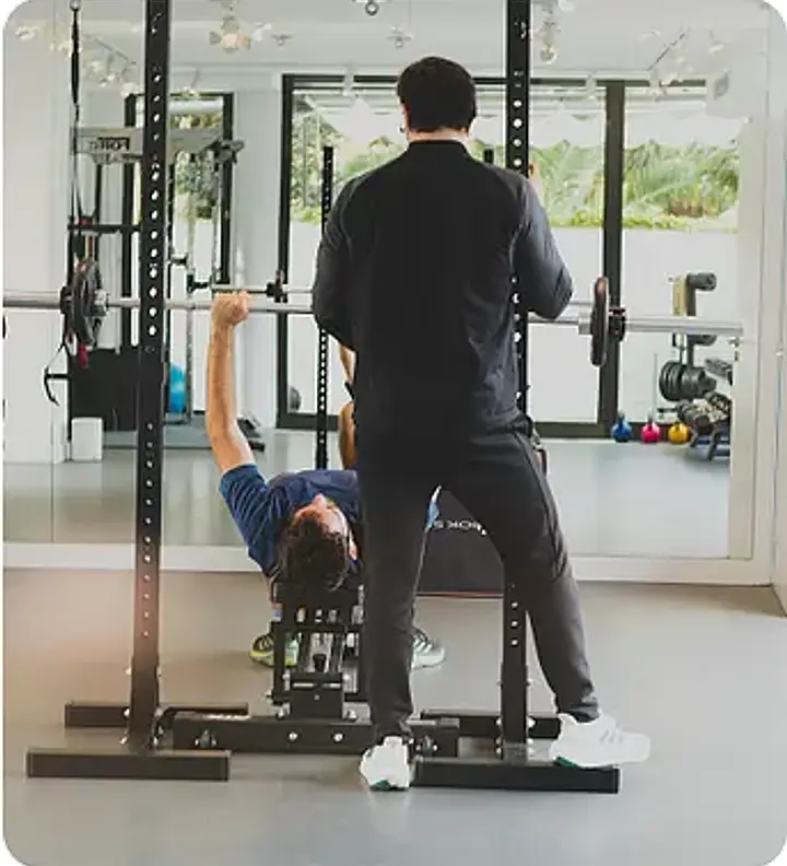 A trainer spotting a client performing a leg press exercise on a machine